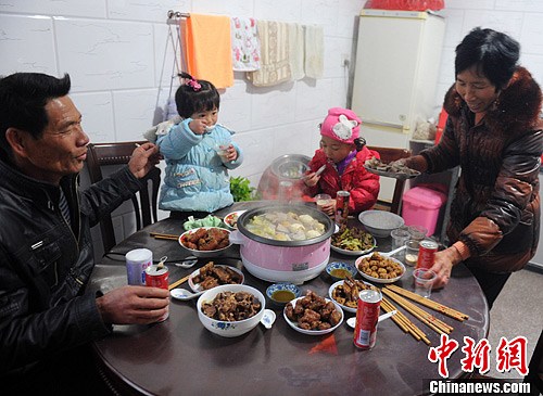 2013年2月9日,中国农历除夕夜,家住著名侨乡福建连江县g头镇定安村62岁的吴存梅、60岁的吴雪娇夫妇,将6岁的大孙女吴若菲、2岁的小孙女吴若芯两“洋留守儿童”打扮得漂漂亮亮。两“洋留守儿童”与爷爷奶奶同吃年夜饭。(中新社/刘可耕