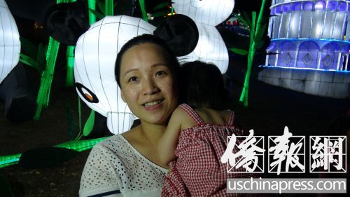 蒋女士抱着女儿在洛县博览会观赏中秋花灯。(美国《侨报》/高睿
