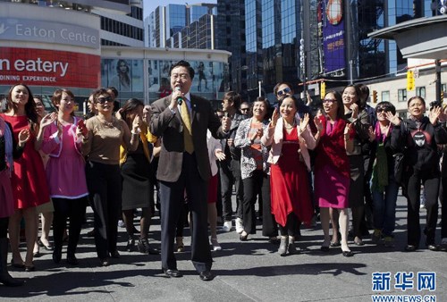 中国侨网9月16日，在加拿大多伦多邓达斯广场，中国驻多伦多总领事房利（前）在演唱会上领唱歌曲。（新华社/邹峥 摄）