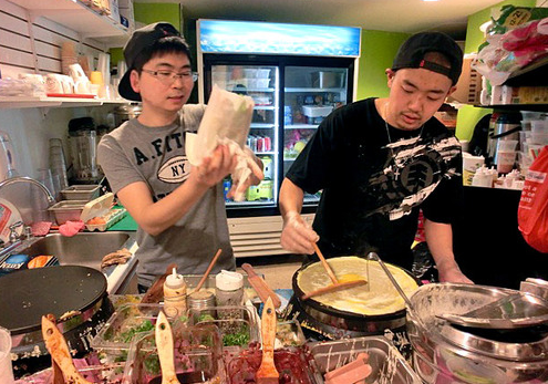 中国侨网美国波士顿正忙着摊煎饼的两个留学生老板。（美国《侨报》）