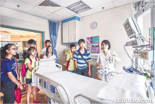 中国侨网华助会受益学生在陈笃生医院职员的带领下，参观医院的加护病房。（新加坡《联合早报》/华助会提供）