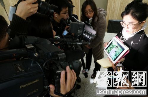 中国侨网律师蔡玟慧通过图片在向媒体展示纪欣然的童年。(美国《侨报》/邱晨 摄)