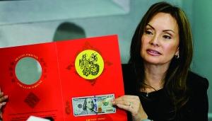 中国侨网美国财政部官员罗茜·里奥斯展示农历羊年限量版100美元“吉利钱”。