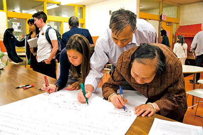 中国侨网到会人员在图书馆倡议板上签字以示支持。右数第三为市议员Michael Flaherty办公室的政策主管Robyn Casper。（美国《星岛日报》）