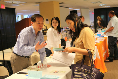 中国侨网波士顿新移民资源博览会上，华埠社区中心志工郭慧明（左一）为民众解答问题。（美国《世界日报》/俞国梁 摄）