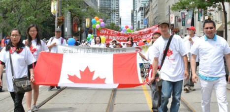 中国侨网国庆大游行声势浩大，游行队伍牵着大幅加拿大国旗，表达对加拿大的热爱。（加拿大《世界日报》/谢君 摄）