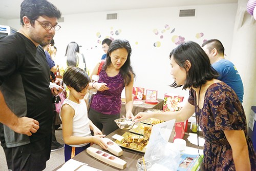 来自不同文化背景的家庭在中秋家庭日限产品尝月饼。(美国《侨报》/陈辰