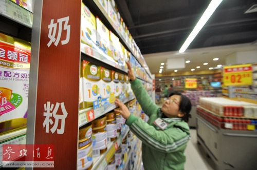 资料图:在一家超市,一名工作人员在整理奶粉