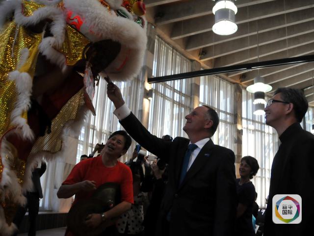 新西兰总理约翰·基(中)向舞狮演员递红包。