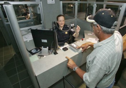 旅客在机场入关，美国海关及边境保护局官员检查当事人的护照与纪录。（海关及边境保护局）
