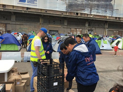 希腊北部大批滞留在伊多梅尼边境地区难民情绪失控，持续堵塞通往前南马其顿的铁路及公路，给希腊社会造成了很大的麻烦，难民和当地居民小范围冲突时有发生。这是4月10日，华人志愿者在难民聚集地现场，分发救助物品。（《欧洲时报》/苏珊娜