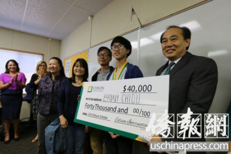 邱少融从爱迪生国际公司代表手中接过了4万元奖学金的支票。(侨报记者邱晨摄)