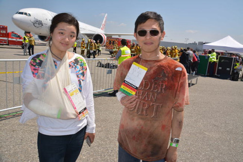 华裔义工于Michelle(左)和杨Joseph(右)参加机场安全演习,扮演受伤者。(美国《世界日报》/启铬