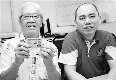 等了50多年才获得公民身份的林金兴(左),开心地展示马来西亚公民卡。来源:中新网
