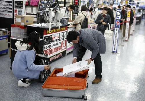 中国游客赴日“爆买”引发全国人大代表热议。图为中国游客在东京一家商场中购物后装箱。(路透社)