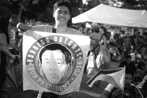 图片说明：一名菲律宾年轻人向记者展示印有杜特尔特头像的宣传品。李昊摄