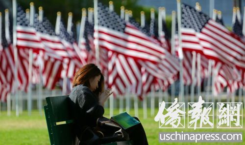 一名女子在旗海旁的长椅上休息。(美国《侨报》/邱晨