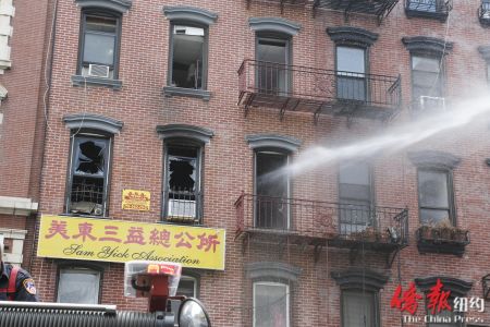 消防员向起火公寓室内喷水灭火。