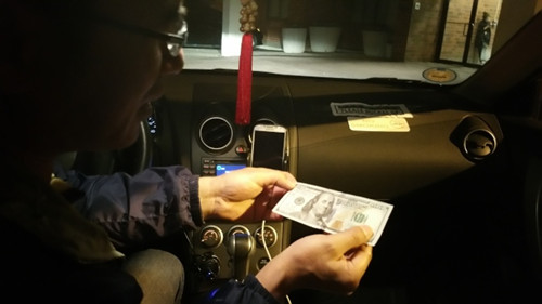 陈先生从非洲裔女顾客手中拿到异常平滑但质感粗糙的百元钞票，还找了对方65元。（美国《世界日报》/许雅钧