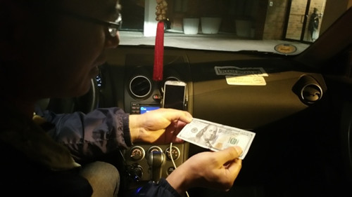 陈先生从非洲裔女顾客手中拿到异常平滑但质感粗糙的百元钞票,还找了对方65元。(美国《世界日报》/许雅钧