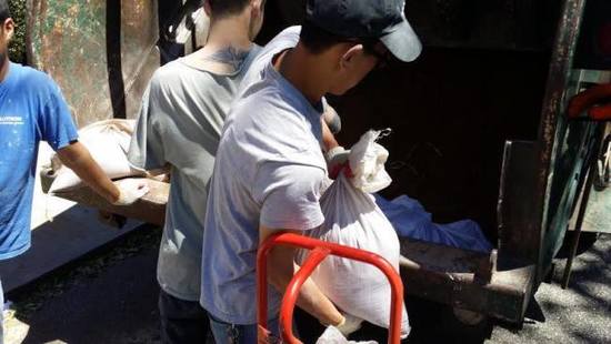 几名华裔男子快速的将白色袋子搬上卡车离去。(美国《世界日报》/黄伊奕