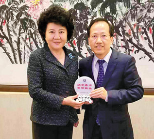 图为梁冠军(右)与国务院侨办主任裘援平合影。