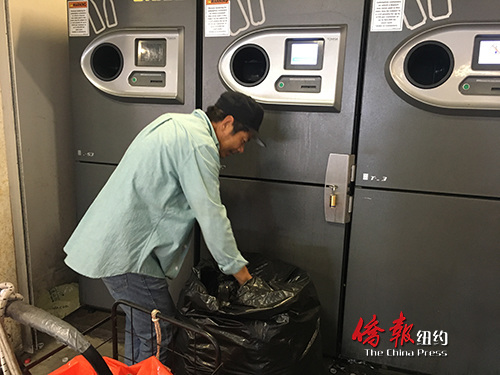 郑先生正把捡到的瓶子放到机器中等待碾碎处理。(美国《侨报》/王伊琳