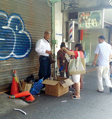 该小贩(左)经常出没在法拉盛售卖仿冒包。(美国《星岛日报》)