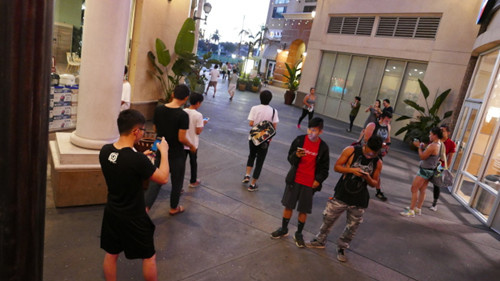 蒙市大西洋时代广场,许多华人驻足聚集捕捉小精灵。(美国《世界日报》)