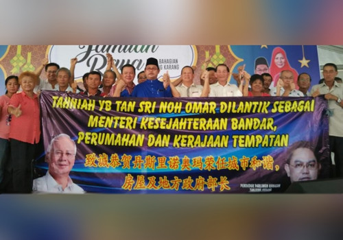 一些丹绒加弄华裔选民高举布条,恭贺诺奥马(左六)重新获委为部长;左五者是潘文俊。(马来西亚《星洲日报》)
