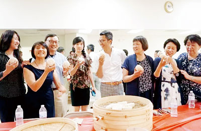 童启华(中)在剑桥中国文化中心向老师们介绍包子。(美国《星岛日报》)