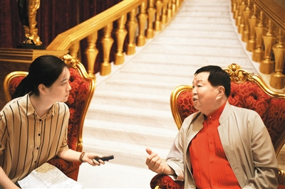 图为本报记者采访严彬(右)。