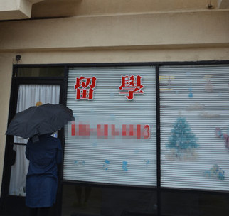 即将面临遣返的一名女生冒雨到中介门前却遭闭门羹。(美国《世界日报》/高梓原
