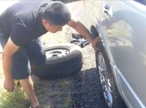 休斯敦华人高速路驾车行驶时，车胎被流弹打爆。图为华人在更换轮胎。（美国《世界日报》）