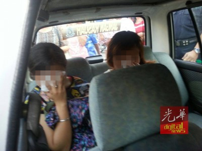 落网的两名女老千被警员押往警局，协助调查。（马来西亚《光华日报》）