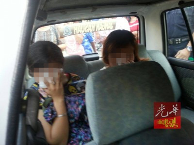 落网的两名女老千被警员押往警局,协助调查。(马来西亚《光华日报》)