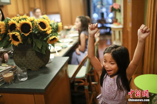 图为爸爸答应为她制作早餐巧克力奶时维罗妮卡举臂欢呼。中新网记者