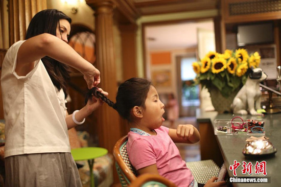 中国侨网图为莎宾娜为维罗妮卡梳头，维罗妮卡常常说起她跟妈妈都有一头黑发。 中新网记者 廖攀 摄