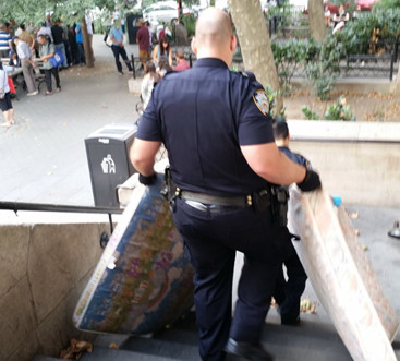 纽约五分局警员将布满臭虫、污渍的流浪汉床垫从哥伦布公园移走。（美国《世界日报》）