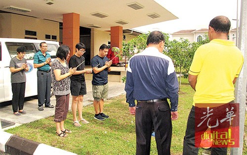 死于心脏病爆发年迈夫妇的3名子女及亲友于医院太平间,持香随道士念经作法。(马来西亚《光华日报》)