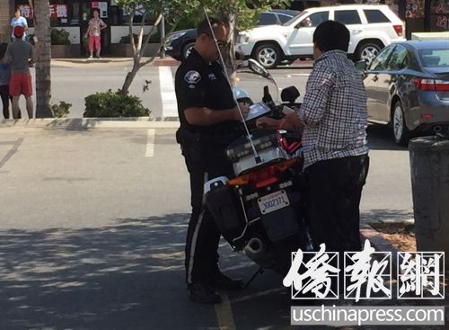 警察正在阿旺戴尔路旁的香港超市停车场给一个华裔路人开罚单。（美国《侨报》/高睿