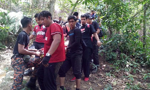 消拯人员在登山客的协助下将死者遗体抬下山。(马来西亚《星洲日报》)