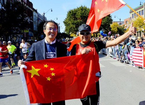 芝加哥举办2016马拉松赛，洪磊（左）为一路携带五星红旗的中国选手签名加油。（美国《世界日报》/董宇