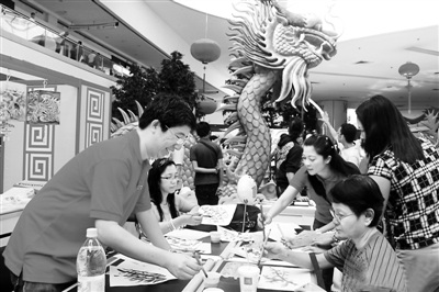 在菲律宾最大商场亚洲商城，由菲华书画世家施扶西家族组织的中国书画课堂吸引了众多菲律宾普通民众的目光。图为几名学员正在学习中国画技法。（图片来源：光明网）