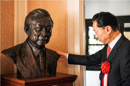 日本前首相鸠山由纪夫近距离欣赏自己的铜像。（日本新华侨报网）