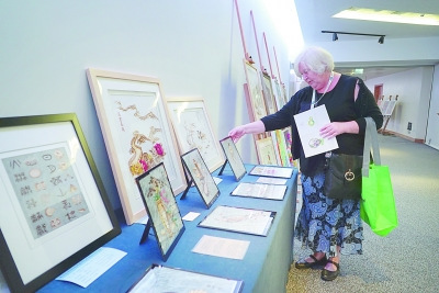 图为一名与会代表观看大会现场展出的中国残疾人艺术作品。本报记者