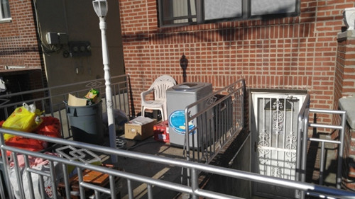 该住宅前院放满垃圾和废弃的家具,地库的门上也被贴查封令。(美国《世界日报》/王靖雯