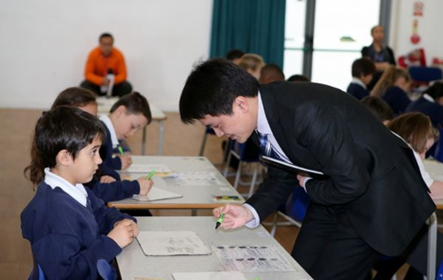 2015年3月17日，来自中国上海徐汇区上海小学的数学老师为英国伦敦东北部埃塞克斯郡的哈里斯小学的学生们上数学课，教授“九九乘法表”在数学计算中的运用。