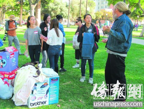 华裔志愿者捐赠衣服给有需要的人,并细心地帮助他们挑选合适尺码。(美国《侨报》/翁羽