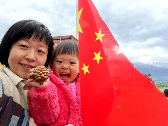 中国侨网于晓瀛抱着女儿等待救援，女儿手拿中国领事馆提供的中国国旗。于晓瀛/摄